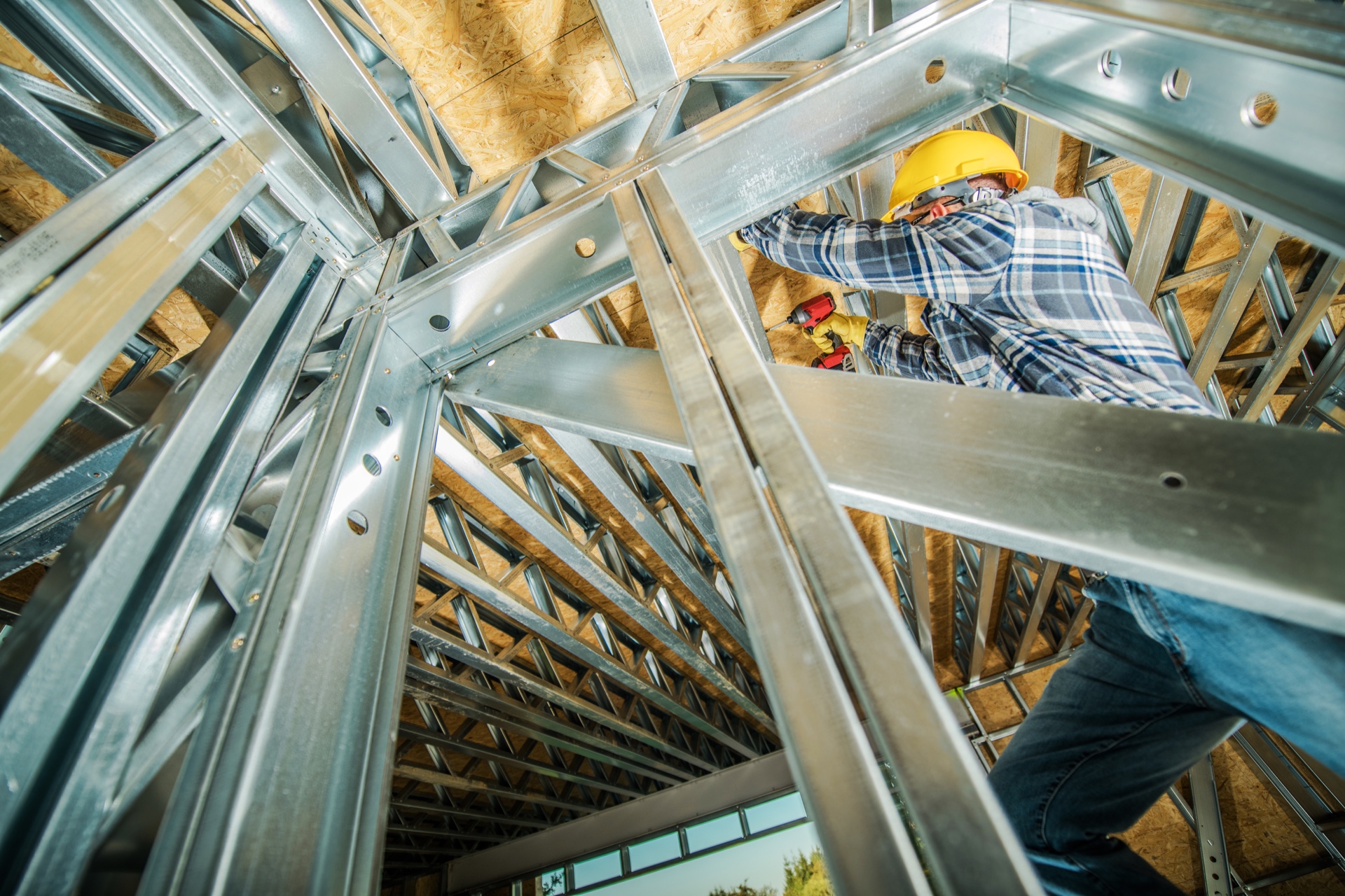Worker securing metal framing connections during CFS installation