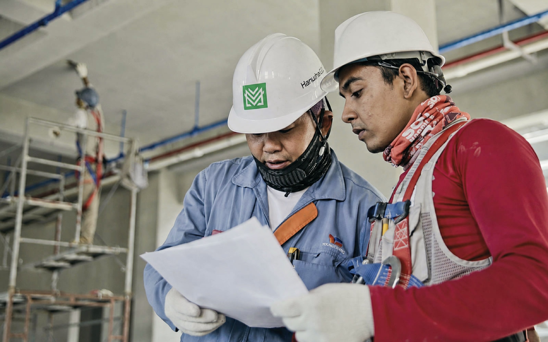 Two construction team members reviewing project drawings on site